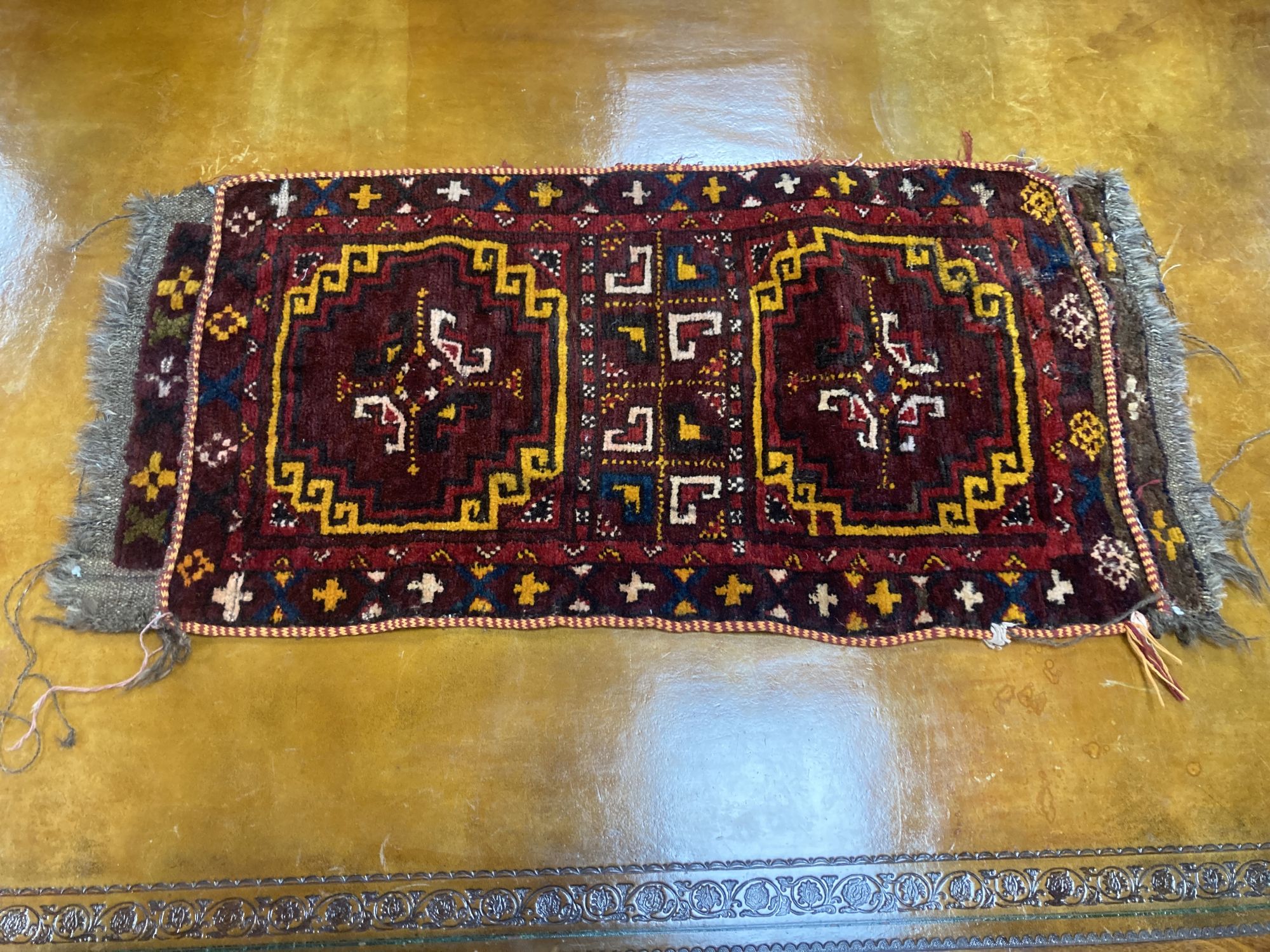 Six Caucasian design mats and a saddlebag, largest 140 x 60cm